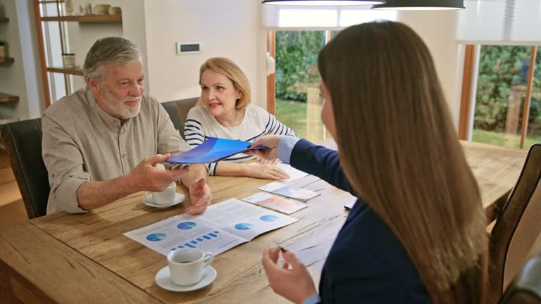 LD Senior couple shaking hands with a female banking advisor in their home