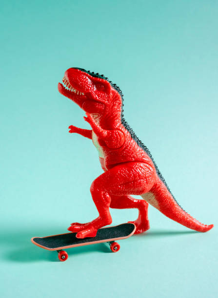 istock Red toy dinosaur skateboarding on blue background. 1500917022