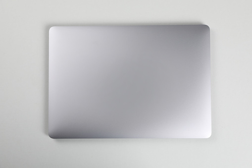 Blank close laptop on white table, top view