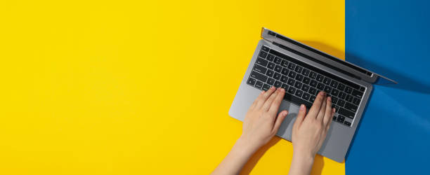 istock Female hands and laptop on yellow - blue background 1500917520