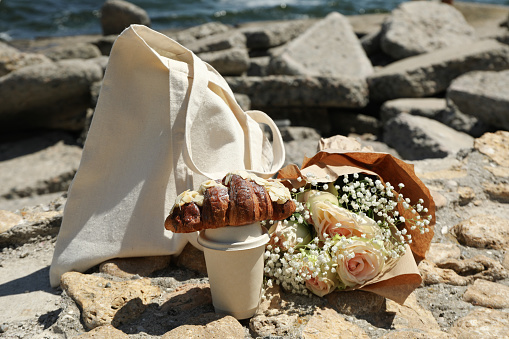 Concept of amazing breakfast near sea with croissant and paper cup of drink