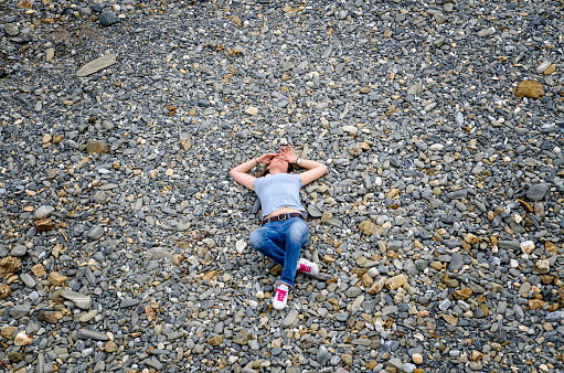 Woman is lying on the stones on the sea beach in Valdoviño