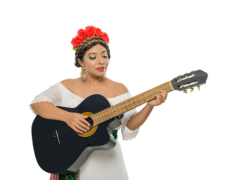 Mexican woman with guitar wearing white dress. Studio portrait.
