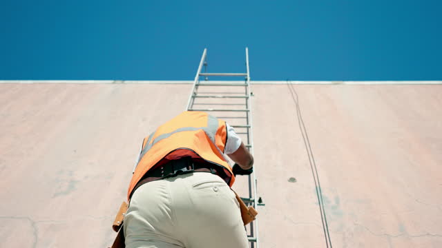 Construction, ladder and building with a man engineer climbing up a wall on a build site. Safety, roof and engineering with a male construction worker or contractor at work on a development project
