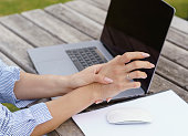 Businesswoman holding her wrist in pain from using laptop computer