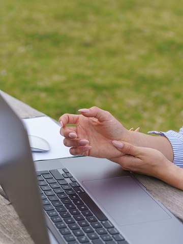 Businesswoman holding her wrist in pain from using laptop computer