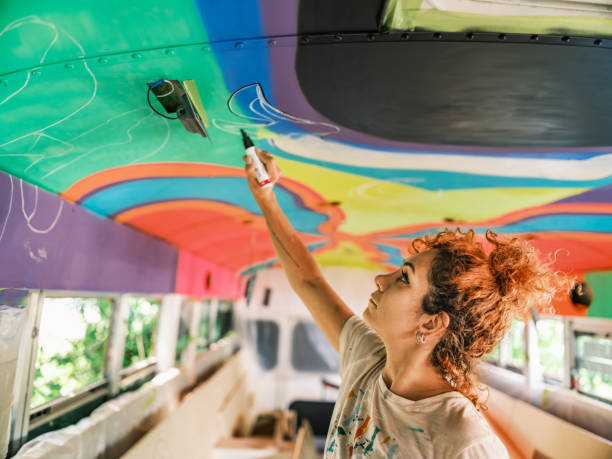 Mid adult Iranian woman artist painting  mural inside party bus stock photo