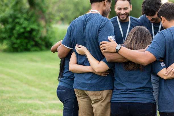 istock Volunteer group stands in circle with arms around each other 1500955809