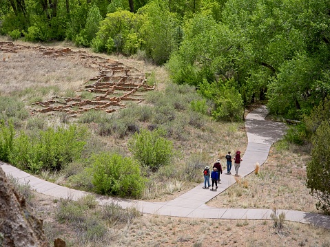 Bandelier national monument, New Mexico - USA, May 12, 2023. A tour group walks through along trail through ancient ruins at Bandelier national monument, New Mexico. Looking at tourists from above.