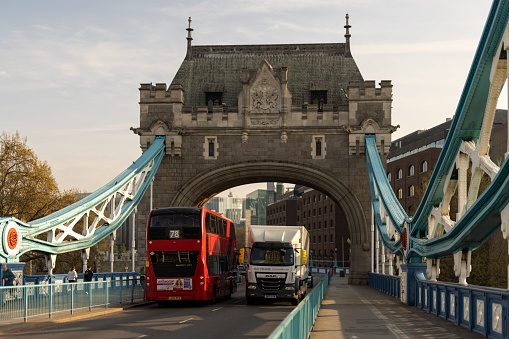 London, United Kingdom – April 30, 2023: Two red double-decker buses traveling on a bridge in London, England, surrounded by other vehicles in the busy city traffic