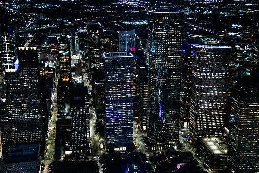 Aerial view of the illuminated streets and buildings of downtown Houston, Texas on an early spring evening just after sunset shot from an altitude of about 1000 feet directly over the city.