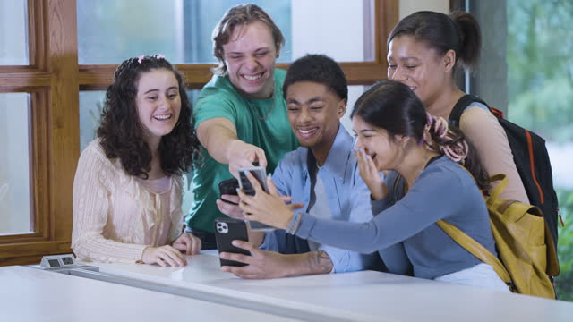 Multiracial teenagers amused by video on mobile phone