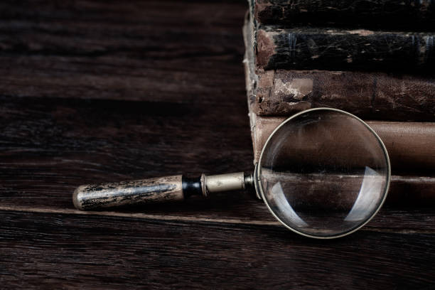 istock Old vintage magnifying glass with books on table 1500984318