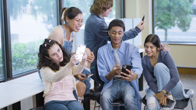 Multiracial teenagers have fun looking at mobile phones