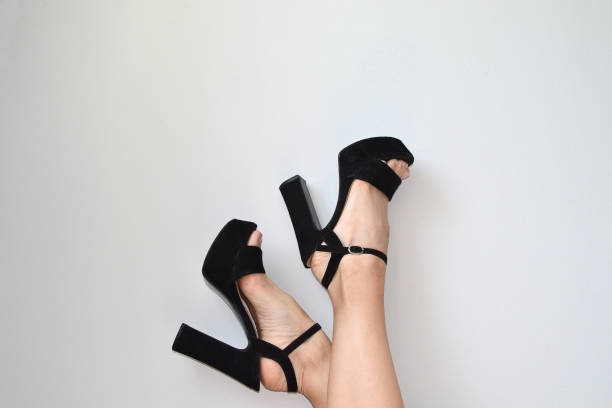 istock Female legs in black sandals on a white background 1501001676