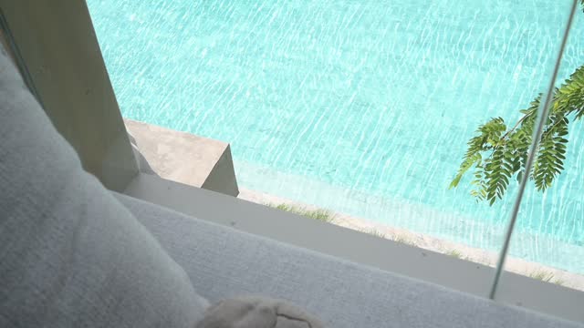 gray pillow put on bed, swimming pool view and slow motion water wave
