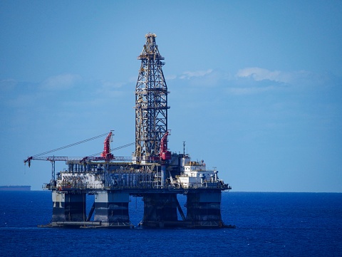 A large offshore oil rig in the middle of a vast expanse of ocean