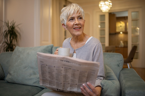 Mature woman reading newspapers