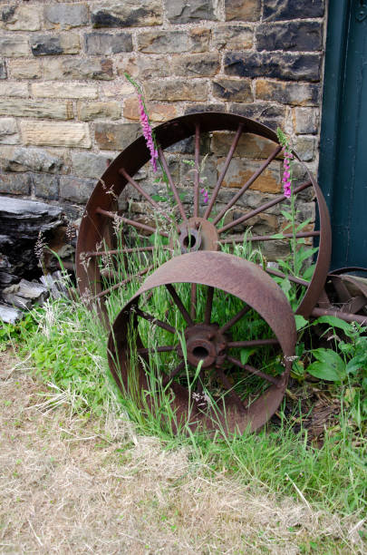 Rusted metal wheels next to stone wall. Abbeydale Industrial Hamlet, Sheffield Museums