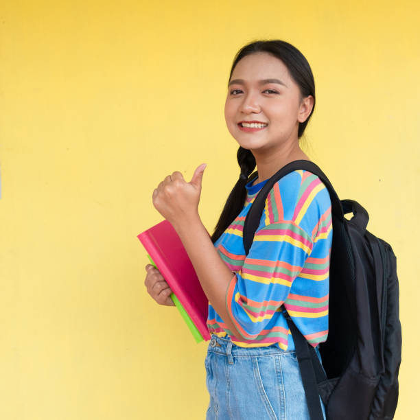 istock Student girl hold book and smiling on yellow background. 1501029765
