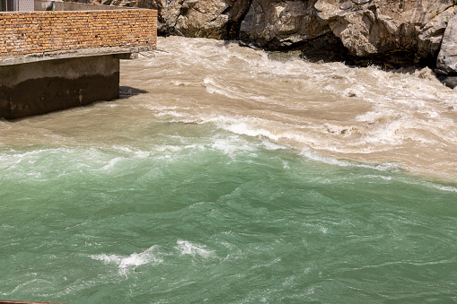 A meeting point of a muddy brown water with a pure green water in the river swat