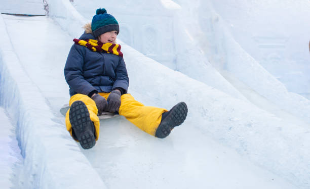 istock happy boy slides down an ice slide in winter outside 1501039328
