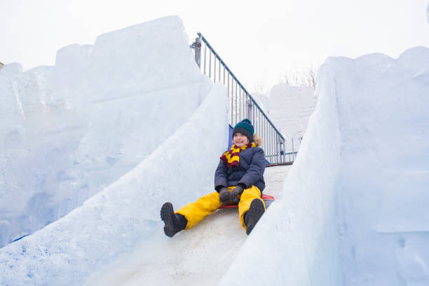 istock happy boy slides down an ice slide in winter outside 1501039403