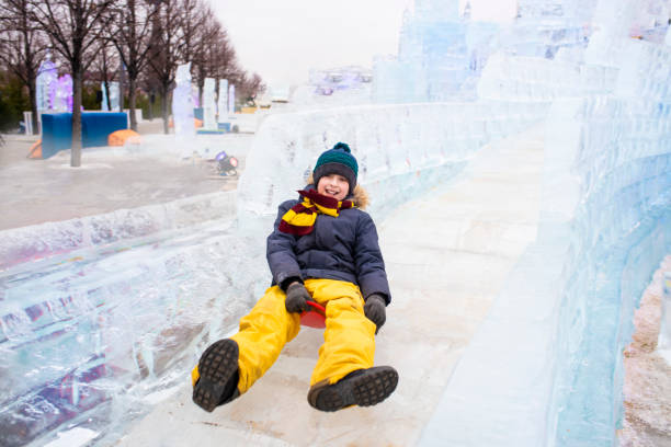 istock happy boy slides down an ice slide in winter outside 1501039434