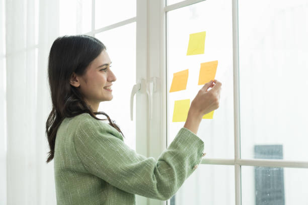 istock Happy young business woman working with post it note or sticky note on glass wall in office. Business people and office concept 1501044192