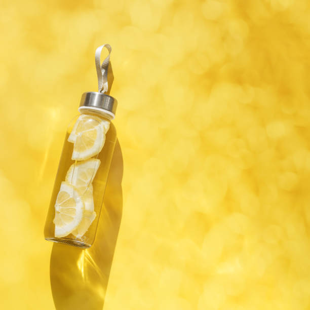istock Cleansing and refreshing Lemon water drink detox, shadow at sunlight on yellow background. Wellness, alkaline diet, eating healthy concept. Stylish glass reusable water bottle, top view 1501044795