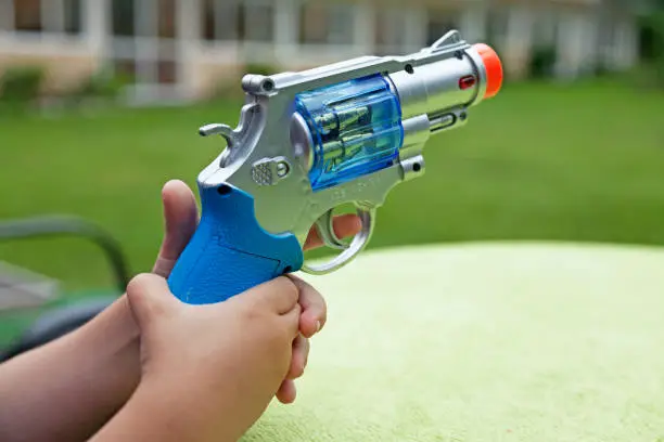 a child holds a plastic toy gun with both hands