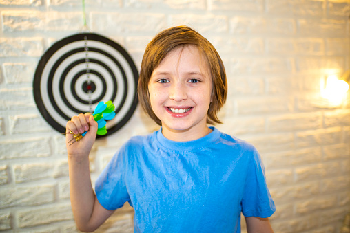 the boy holds a dart in his hand, he is going to throw it at the target, the child plays darts