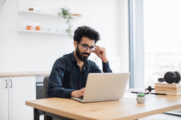 istock Man in glasses using laptop at writing desk in kitchen 1501055194
