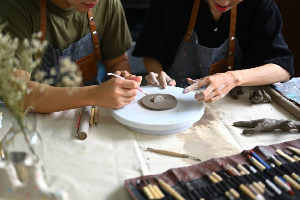istock Cropped shot two smiling man dressed in an aprons creating handmade ceramic plate in a pottery workshop. 1501056702