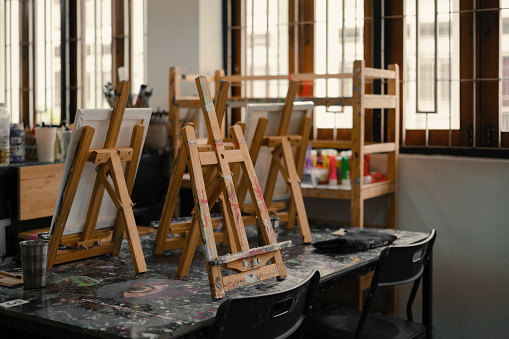 Interior of the creative art workshop with wooden easels and brushes and tools.