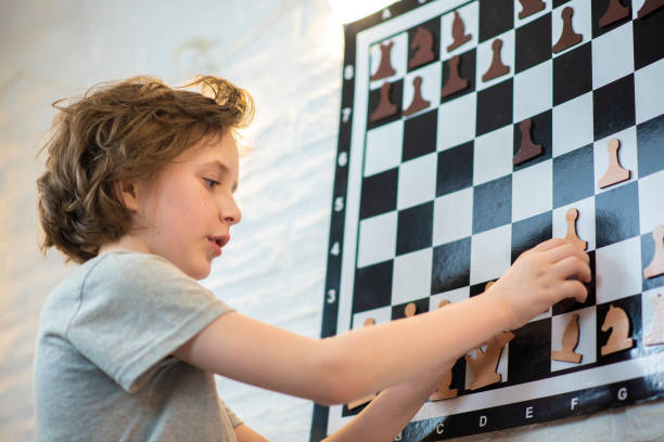 istock the boy solves chess problems. the child stands in front of a wall-mounted magnetic chess board for learning. 1501057808
