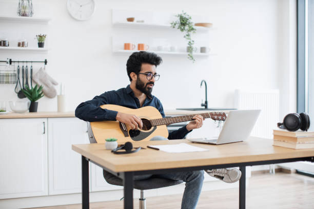 istock Musician composing song with guitar and computer at home 1501059680