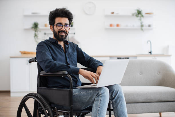 istock Man in wheelchair staying with laptop in open-plan kitchen 1501059750