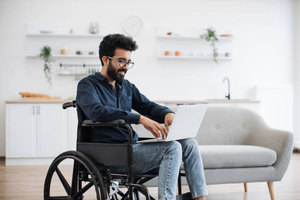 istock Man in wheelchair staying with laptop in open-plan kitchen 1501059758