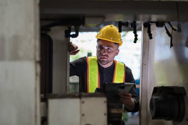 männlicher ingenieurarbeiter, der arbeitet und die teilequalität der drehmaschine in der industriefabrik prüft, trägt sicherheitsuniform, helm. männlicher techniker, arbeiter, der teile der maschine in der werkstatt wartet - cnc vehicle part quality control industry stock-fotos und bilder