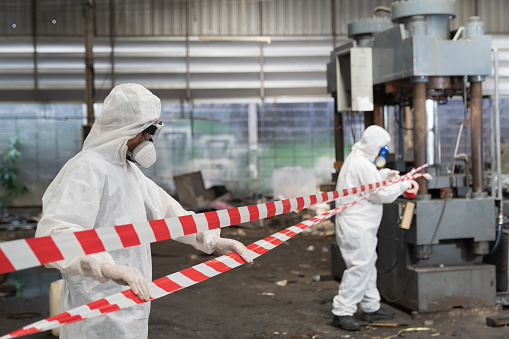 Chemical leak and safety first concept. Group of chemical specialist wear safety uniform, gas mask employ line white and red stripe signal no entry chemical dangerous area in the industry factory