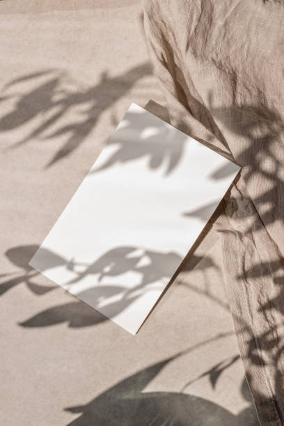 istock Empty paper card mockup with copy space on neutral beige linen cloth background with aesthetic floral sunlight shadow, sustainable business brand template, wedding invitation design 1501060324