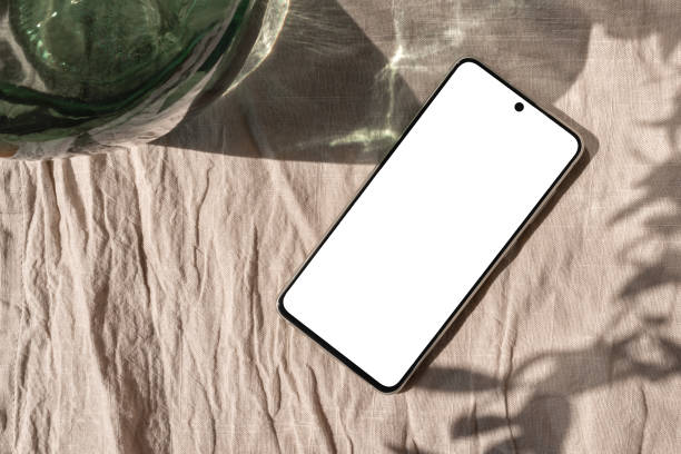istock Empty smartphone screen mockup on beige linen tablecloth with aesthetic sun light shadow, lifestyle business brand template 1501060401