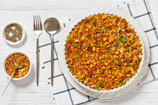 Chicken Rice Casserole D Iberville topped with french fried onion and crumbled crackers in baking dish on white wood table, horizontal view from above, flat lay