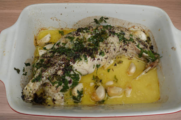 Monkfish stuffed with garlic cooked in the oven with lemon juice, olive oil, parsley and dried seaweed Monkfish stuffed with garlic cooked in the oven with lemon juice, olive oil, parsley and dried seaweed stargazer fish stock pictures, royalty-free photos & images