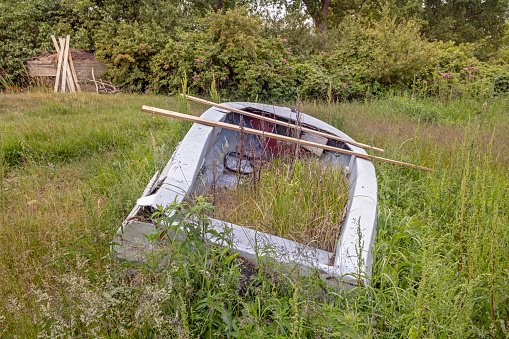 Old dinghy left to decay in a grass field close to the water