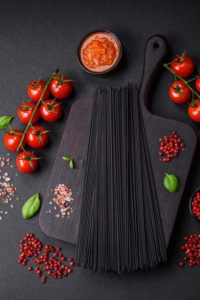 istock Raw black spaghetti pasta with tomatoes, salt, spices and herbs 1501069491