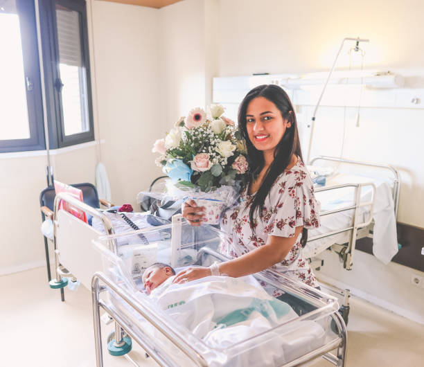 donna con il suo bambino appena nato in un ospedale e tenendo in mano un mazzo di fiori - men giving balloon women foto e immagini stock