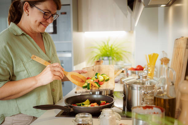istock Mature woman adding chopped vegetables to a frying pan 1501071840