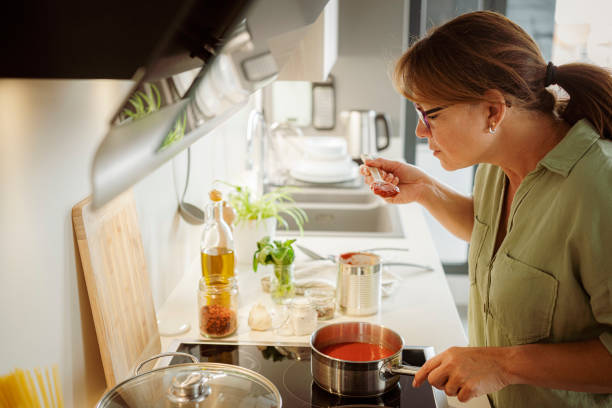 istock Woman cooking and tasting tomato sauce 1501072373